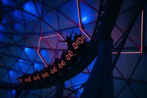 Dunkle Themenfahrt mit Fahrgästen unter blau-roter Lichtinszenierung